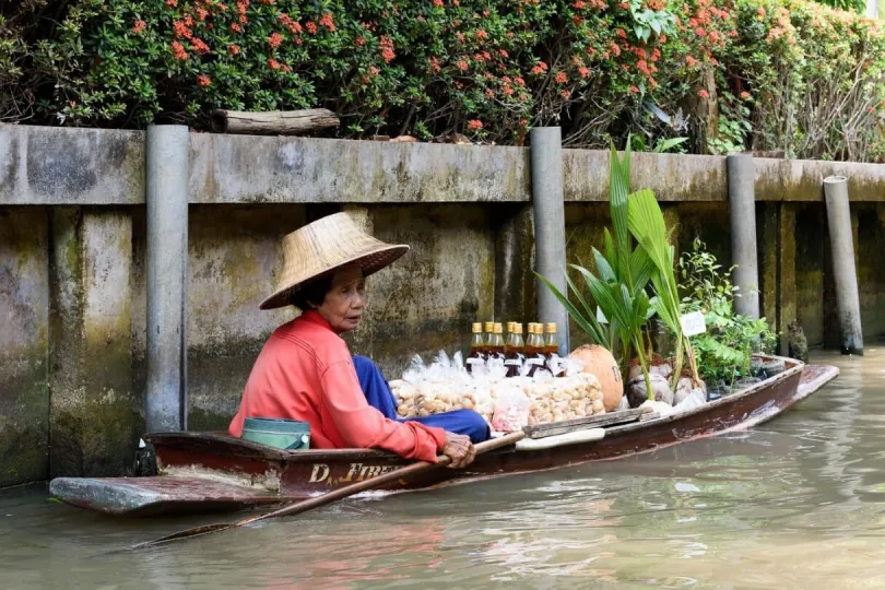 Eine Frau sitzt auf ihrem Holzboot und verkauft Lebensmittel