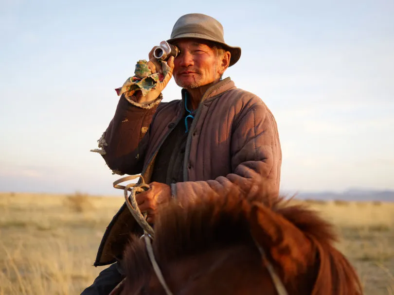 Ein Mann auf einem Pferd in der Mongolei mit einem Fernglas