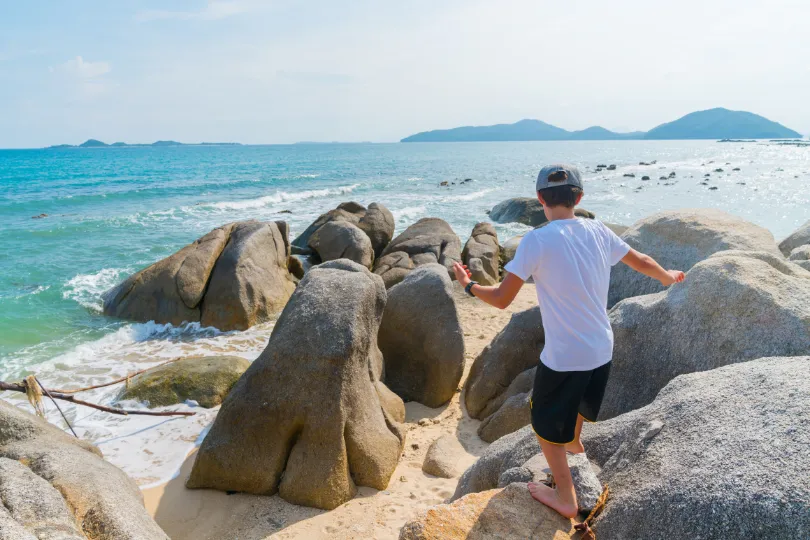 Kind spring über Steinen auf Koh Samui